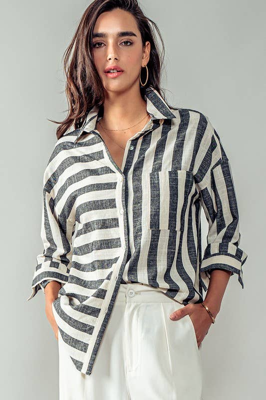 A woman wearing a long-sleeved, vertical and horizontal striped shirt in black and white, paired with white pants.